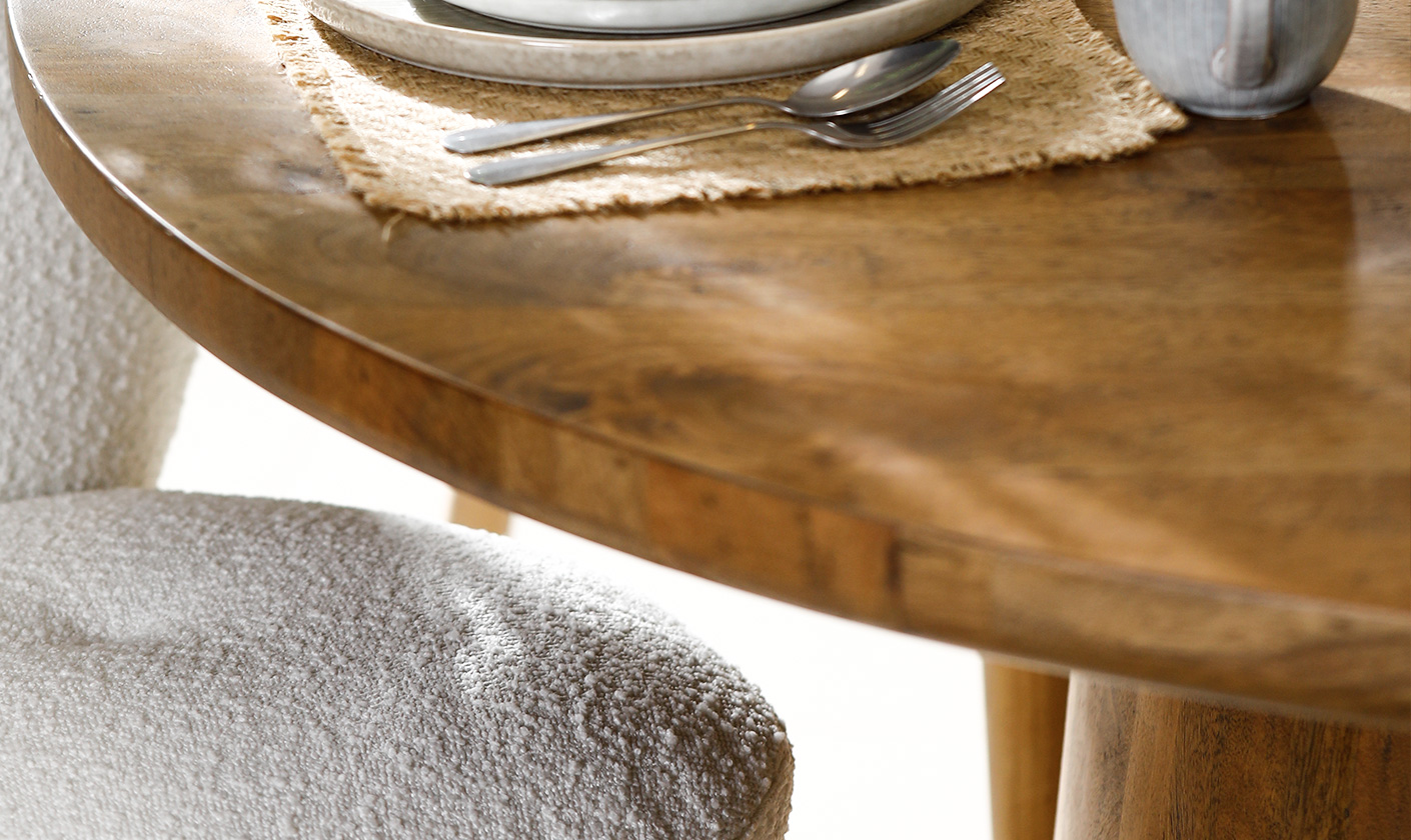 Rustic wooden dining table styled with ceramic plates and silver cutlery for an elegant dining setup.